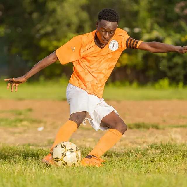 Player striking the ball on a dirt pitch